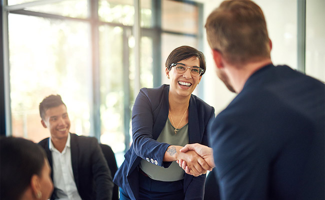 Woman shaking hands with a colleague in an office.