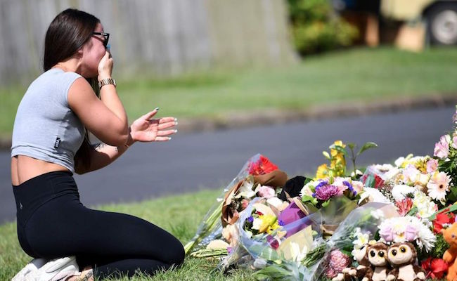 A friend of Hannah Clarke reacts at a makeshift shrine.